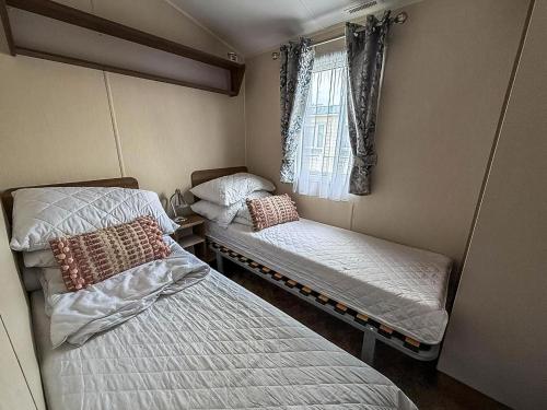 a small room with two beds and a window at Caravan With Large Decking At Coopers Beach Holiday Park Ref 49012Sv in East Mersea