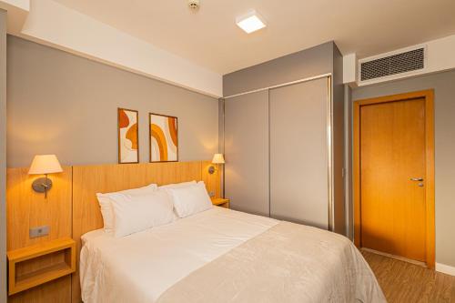 a bedroom with a white bed with a wooden headboard at STD - Anora Spaces - Stadium Alphaville in Barueri
