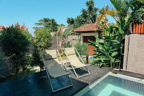 two chairs sitting next to a swimming pool at BRAND NEW! 2BR Villa in SouthKuta With Pool in Ungasan