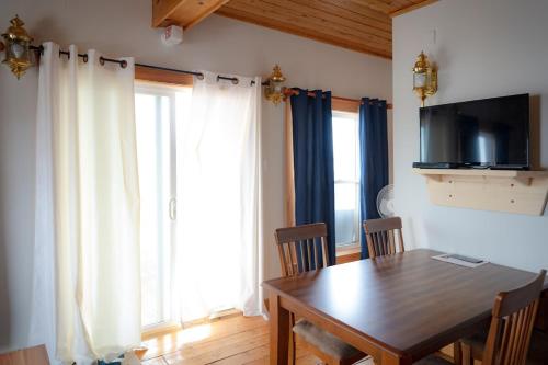 a dining room with a table with chairs and a television at Boathouse in Chéticamp