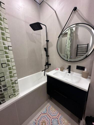 a bathroom with a sink and a mirror and a tub at New Apartment in the City Center & Restaurants and Cafe & Famous sightseeings in Almaty