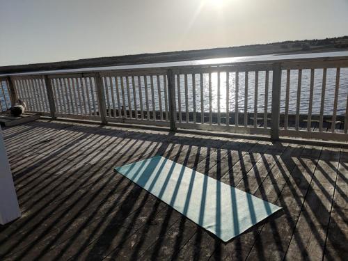 a mat on the deck of a balcony overlooking the water at Boathouse in Chéticamp