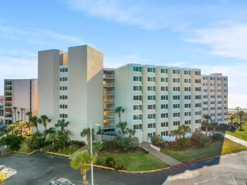 a large white building with palm trees in a parking lot at Renovated Beach Front Ocean View Condo Tog 723 in Panama City Beach