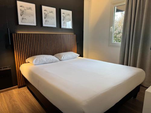 a bed with two pillows on it in a bedroom at Tulip Inn Beaune in Beaune