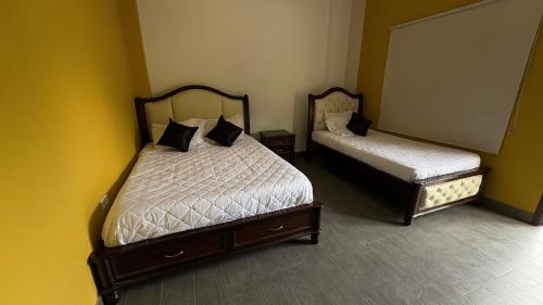 two beds in a room with yellow walls at hacienda hotel texas in Durania