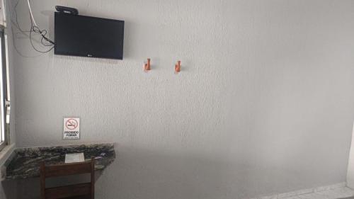 uma sala com uma TV em uma parede branca em Pousada Rout Bikers Penedo em Penedo