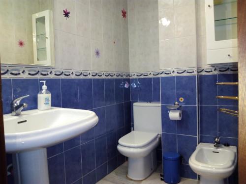 Baño de azulejos azules con aseo y lavamanos en Luxury Flat, en Málaga
