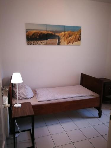 a bed in a room with a table and a picture on the wall at City Appartements Köthen in Köthen