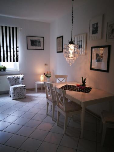 a dining room with a table and chairs and a chandelier at City Appartements Köthen in Köthen