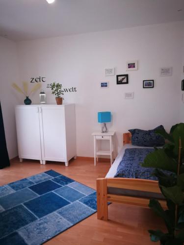 a bedroom with a bed and a white wall at City Appartements Köthen in Köthen
