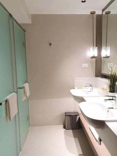 a bathroom with two sinks and two mirrors at Novotel Hotel Residences Manila by AMORE Suites in Manila