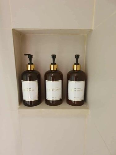 three bottles of soap are sitting on a shelf at Novotel Hotel Residences Manila by AMORE Suites in Manila