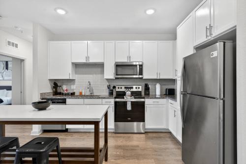 a kitchen with white cabinets and a stainless steel refrigerator at Nice 2 BR Apt|King Bed|Pool |Gym|Clse 2 Beach/Mayo in Sandalwood