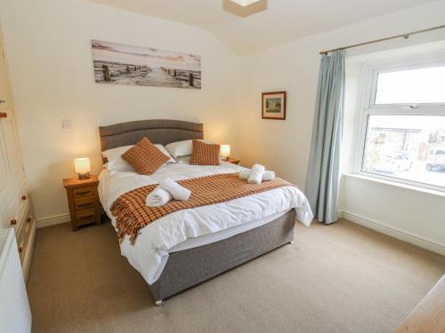 a bedroom with a bed with two pillows and a window at Centenary Cottage in Skipton