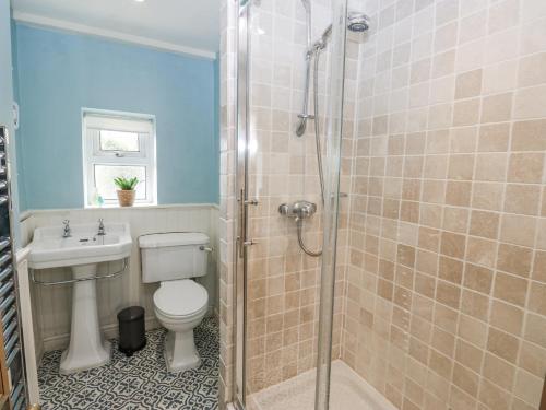 a bathroom with a shower and a toilet and a sink at Centenary Cottage in Skipton