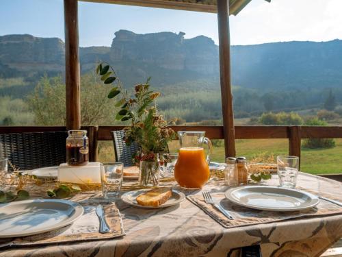 a table with plates of food and a view of mountains at Camelroc Guest Farm in Fouriesburg