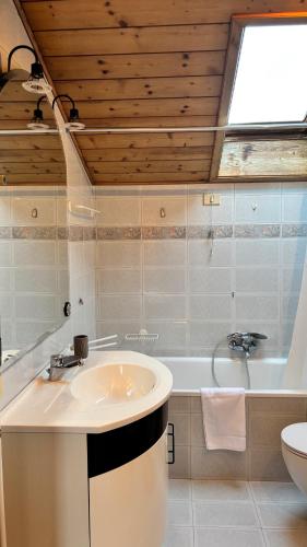 a bathroom with a sink and a bath tub at Apartment Holzsuite in Malosco