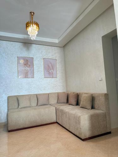 a couch in a living room with a chandelier at BARAKA APPART in Selouane