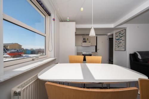 a dining room with a white table and chairs and a window at Ilulissat Stay - Nanna's Villa - 1 in Ilulissat