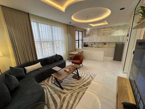 a living room with a black couch and a kitchen at فندق روابي جاردن إن ابها Rawabi Garden In ABHA Hotel in Abha