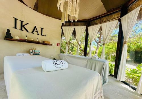 two beds with white sheets in a room with windows at Ikal Island Garden in Isla Mujeres