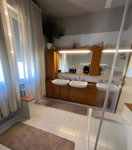 a bathroom with three sinks and a large mirror at Homecoming apartment in Guastalla