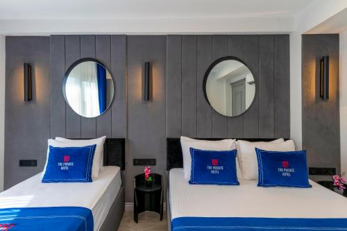 two beds with blue pillows in a room with two mirrors at The Private Airport Hotel in Istanbul