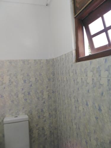 a bathroom with a toilet and a window at Mayon Guest in Tangalle