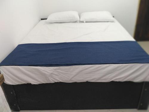 a bed with a blue and white blanket on it at Mayon Guest in Tangalle
