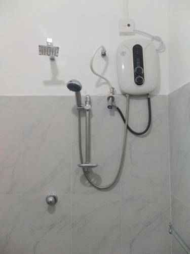 a shower in a bathroom with a phone on the wall at Mayon Guest in Tangalle