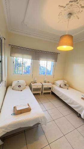 two beds in a room with two windows at Anfa Training Bed and Breakfast in Bouznika