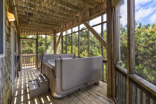 a screened in porch with a tub on a deck at 8455 - Mad Hatteras in Avon