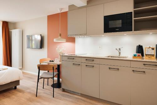 a kitchen with white cabinets and a table and a bed at Stay Sunday in Zürich