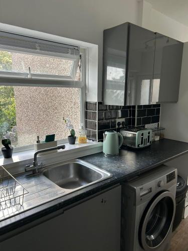 a kitchen with a sink and a washing machine at Ty Abertawe in Cockett