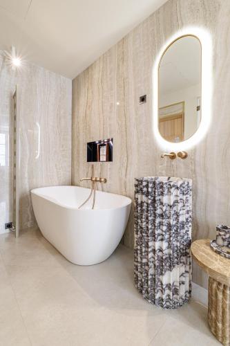 a bathroom with a white tub and a mirror at Le Dortoir Boutique Suites in Nice
