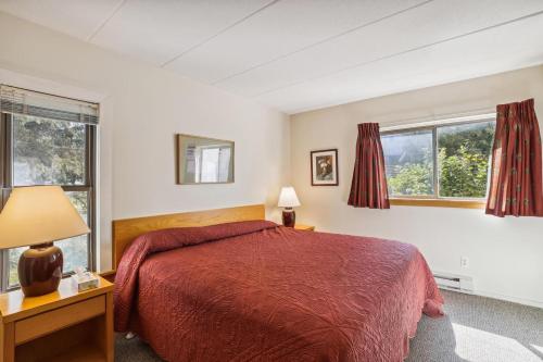 Un dormitorio con una cama roja y dos ventanas. en Pinnacle E09, en Killington Village