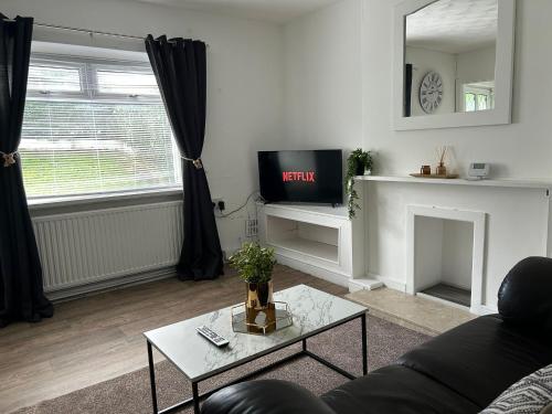a living room with a couch and a tv at Ty Abertawe in Cockett