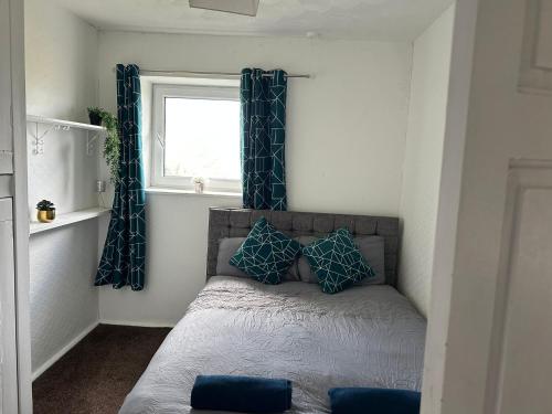 Un dormitorio con una cama con almohadas azules y una ventana. en Ty Abertawe, en Cockett