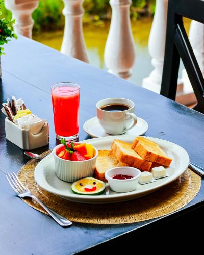 a plate of breakfast food on a table with a drink at Hotel Villa del Lago in Flores