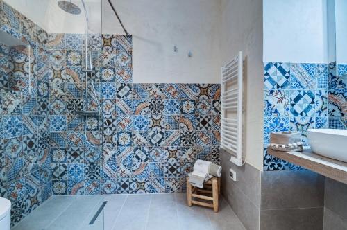 un bagno con piastrelle bianche e blu sul muro di Masseria La Macchiola & Corti del Mito a Spongano