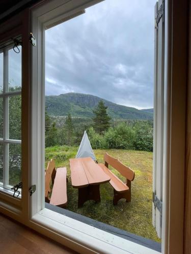 a picnic table and two benches outside a window at Small cabin at Seljestad in Utsikten