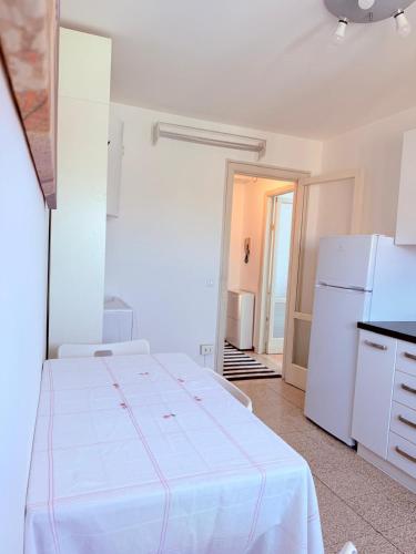 a white room with a bed and a refrigerator at bilocale vicino alla metro in Brescia