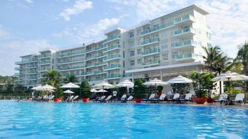 a large hotel with a large swimming pool with chairs and umbrellas at Căn hộ c414 in Ấp Phú Tịnh (2)