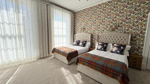 a bedroom with two beds and a chair and curtains at Armadillo Guest House in Edinburgh