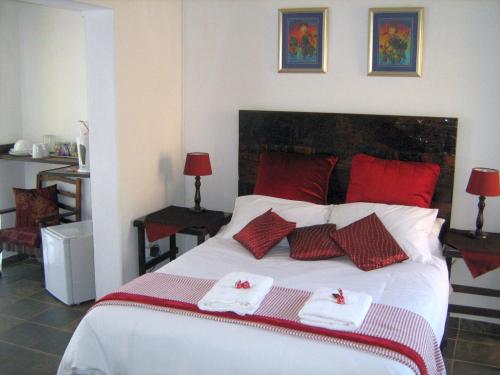 a bedroom with a bed with red and white towels on it at Ukarimu Guest House in Klerksdorp