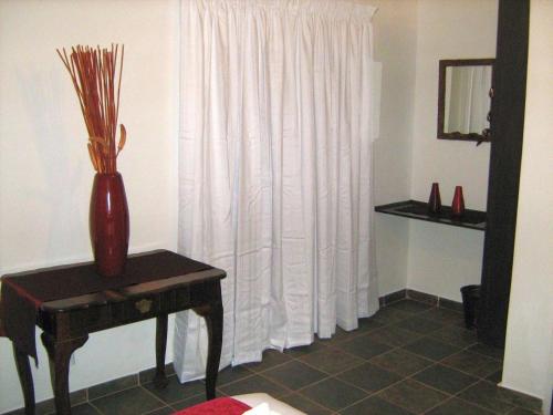 a vase sitting on a table next to a window at Ukarimu Guest House in Klerksdorp