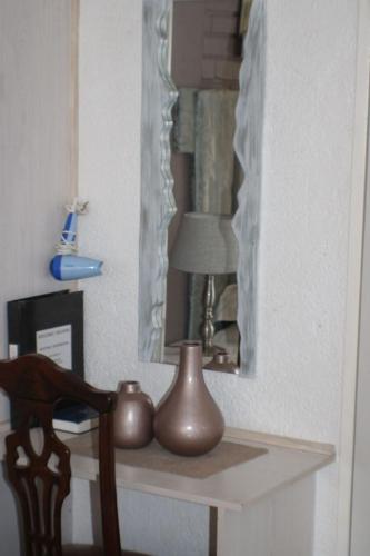 a table with a lamp and a mirror and a chair at Ukarimu Guest House in Klerksdorp