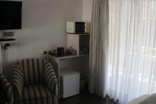 a living room with a chair and a microwave at Ukarimu Guest House in Klerksdorp