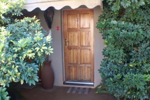 a wooden door with plants in front of a building at Ukarimu Guest House in Klerksdorp