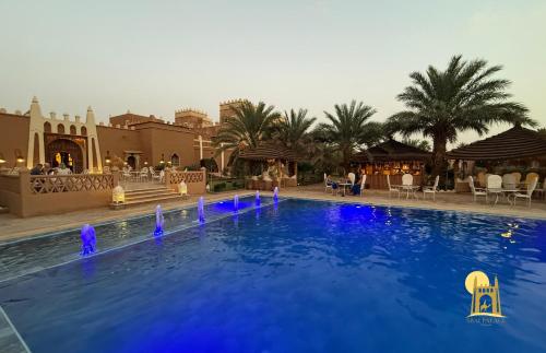 a swimming pool with blue lights in a resort at hotel riad kasbah sbai palace in Mhamid